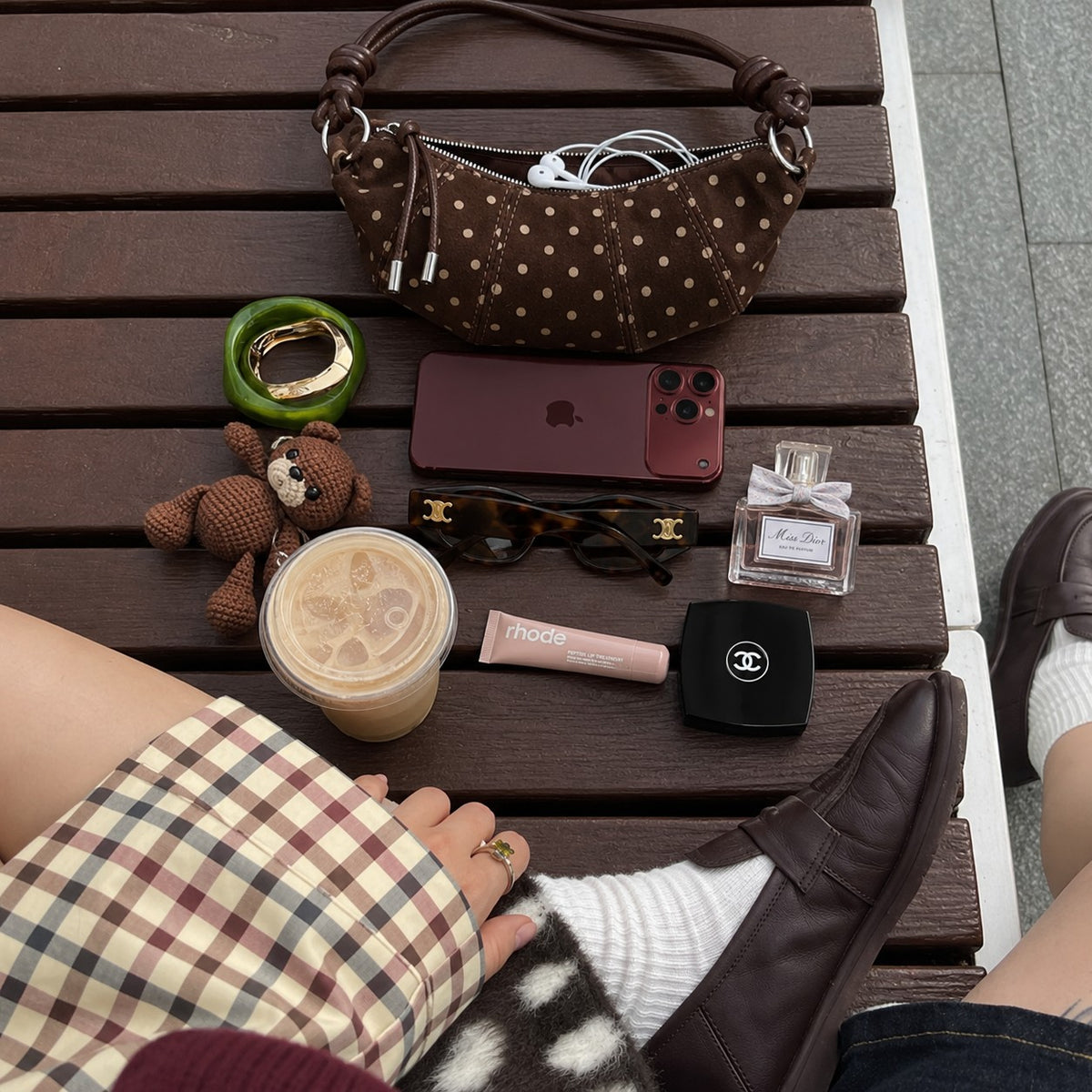 Briochelle Polka Dot Croissant Shoulder Bag - Chocolate Brown - on a bench with everyday essentials
