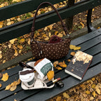 Briochelle Polka Dot Croissant Shoulder Bag - Chocolate Brown - on an autumn park bench