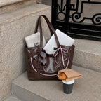 Clovara Glossy Tote Bag - Brown - packed with a laptop and newspaper on stone steps