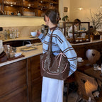 Clovara Glossy Tote Bag - Brown - worn on the shoulder in a cafe