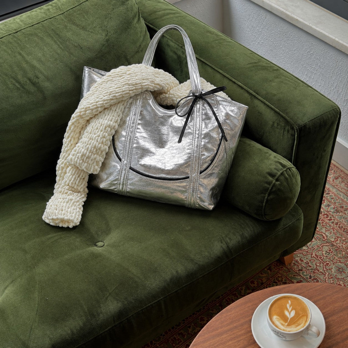 Clovara Glossy Tote Bag - Silver - on a green velvet sofa