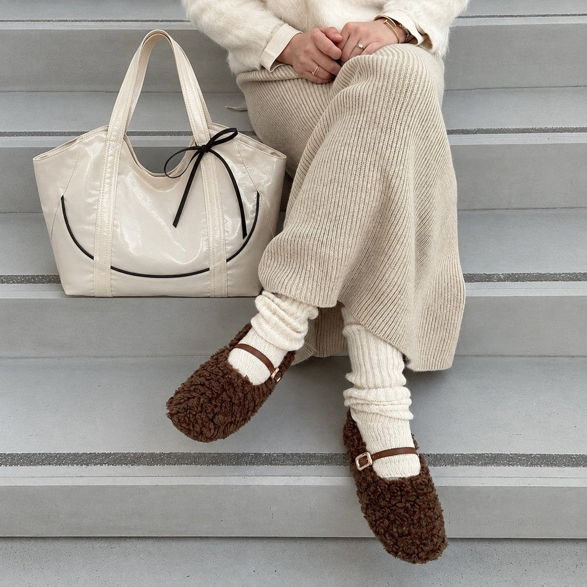Clovara Glossy Tote Bag - White - beside a knit skirt on the steps