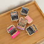 Écrinette Kiss-Lock Jewelry Case - six colours open on a tray