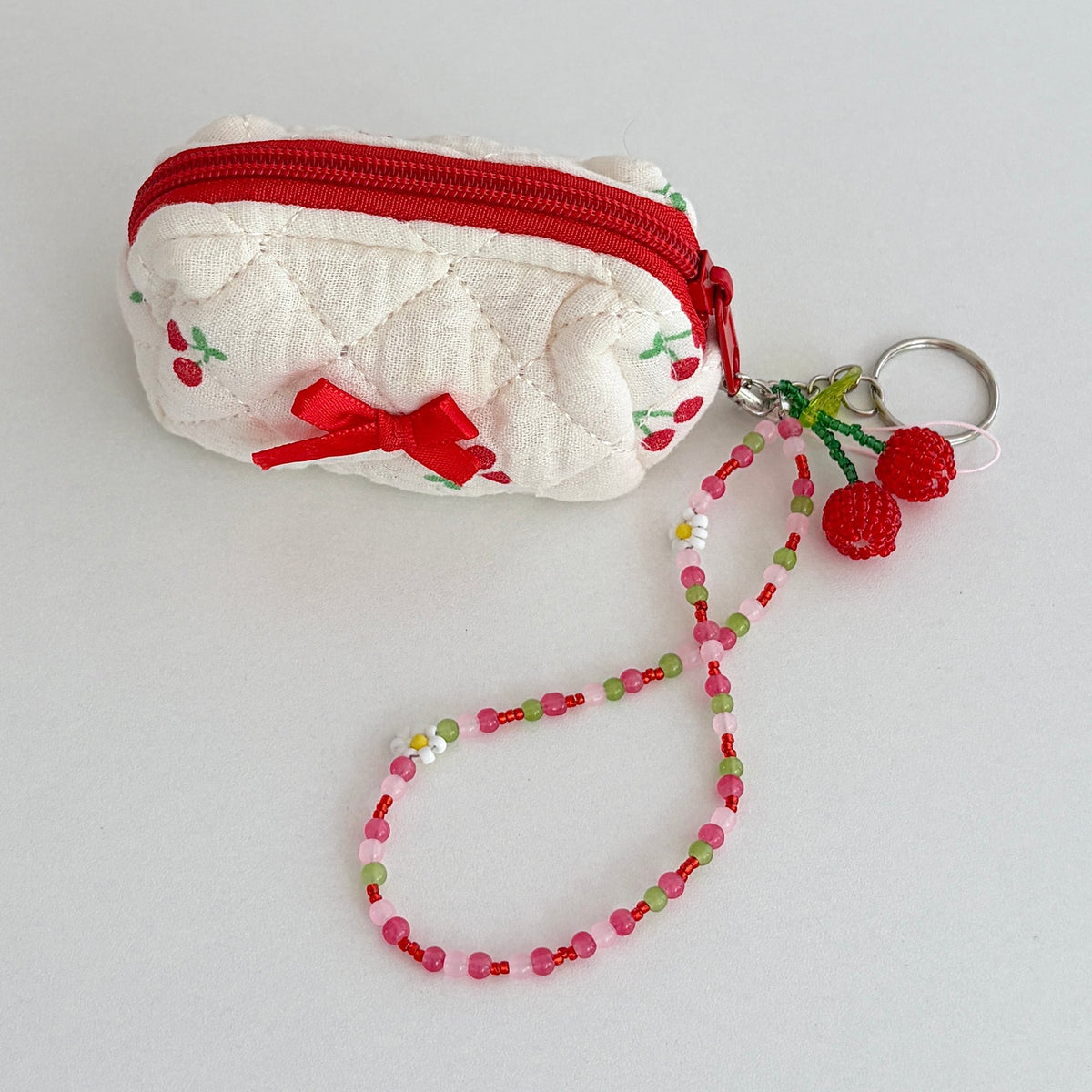 Orchard Swing Beaded Cherry Phone Charm - clipped to a quilted coin pouch