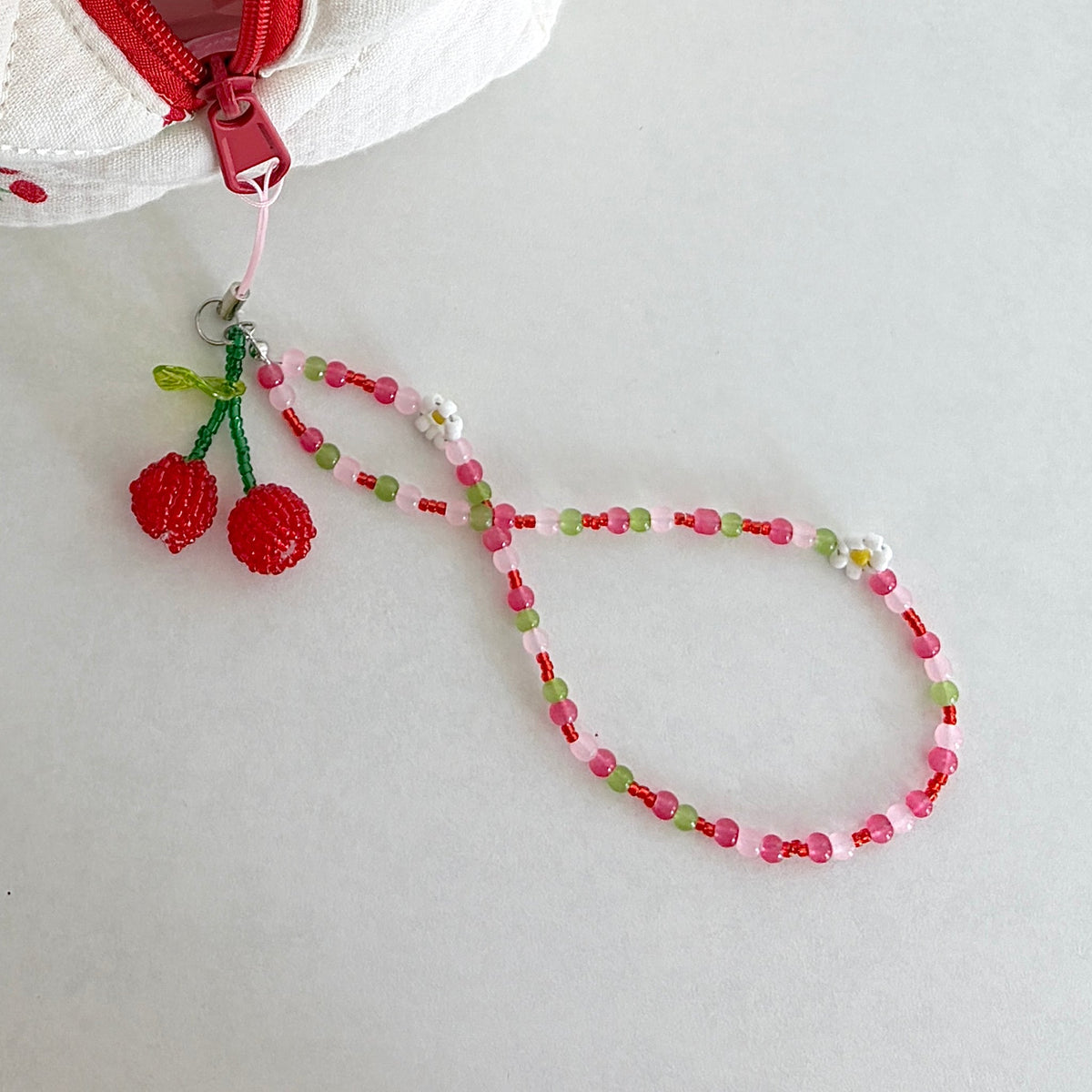 Orchard Swing Beaded Cherry Phone Charm - close-up hanging from bag zipper
